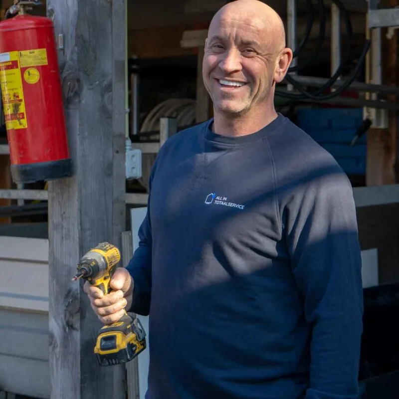 Een lachende Pascal houdt een boormachine vast tijdens een Verbouwing in Tilburg