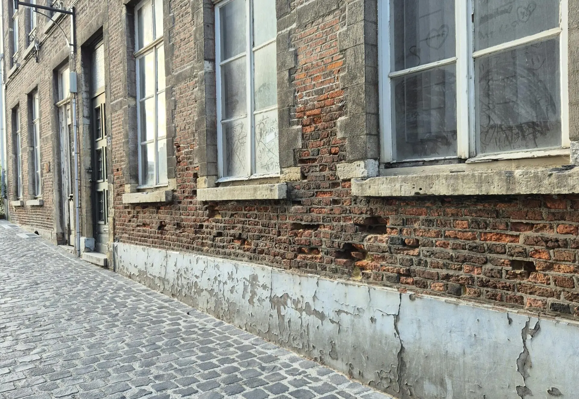 Straat met bakstenen gebouwen met beschadigde, verouderde gevelvoegen